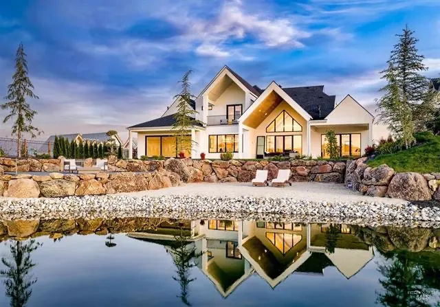 Luxury new-construction home reflected in a private pond