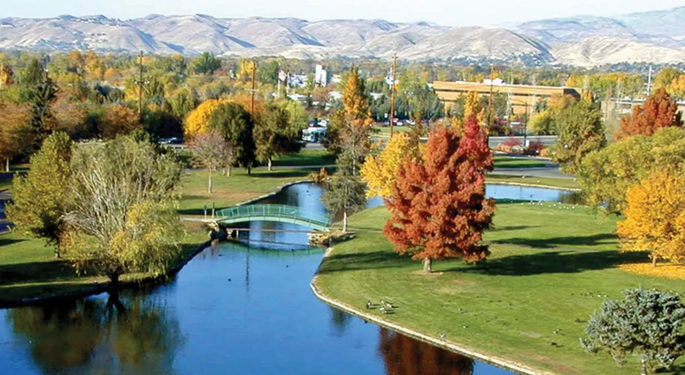 Boise park lagoon and footbridge in fall colors with the foothills beyond