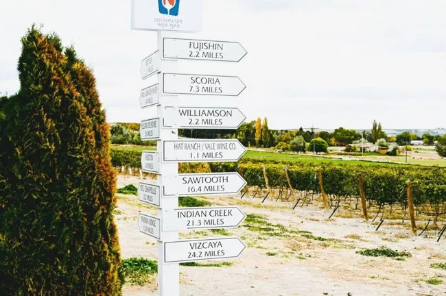 Signpost listing Sunnyslope wineries beside a vineyard