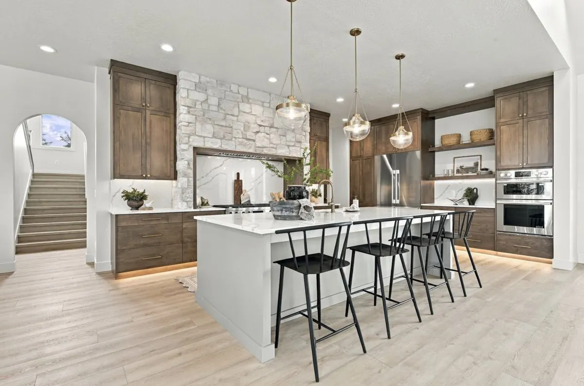 Luxury kitchen with stone hood wall, wood cabinetry and a large island