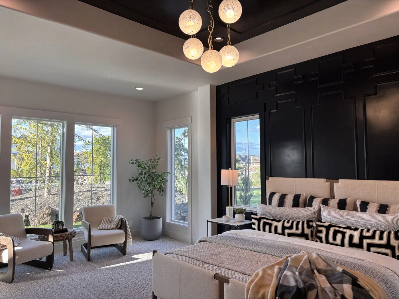 Professionally styled primary bedroom with layered bedding and a sitting area