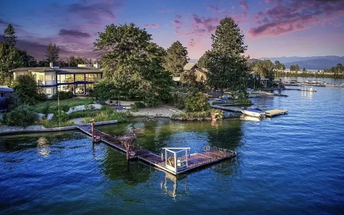 Waterfront home with a private dock on a calm lake at sunset