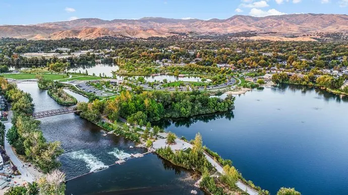 Aerial view of Esther Simplot Park ponds and the Boise River, with the Foothills behind
