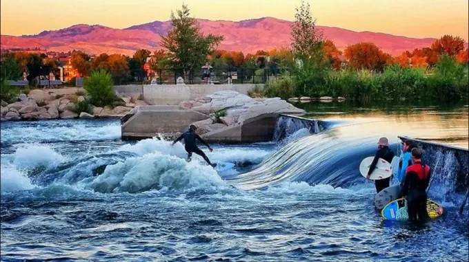 River surfers on the wave at the Boise Whitewater Park at sunset